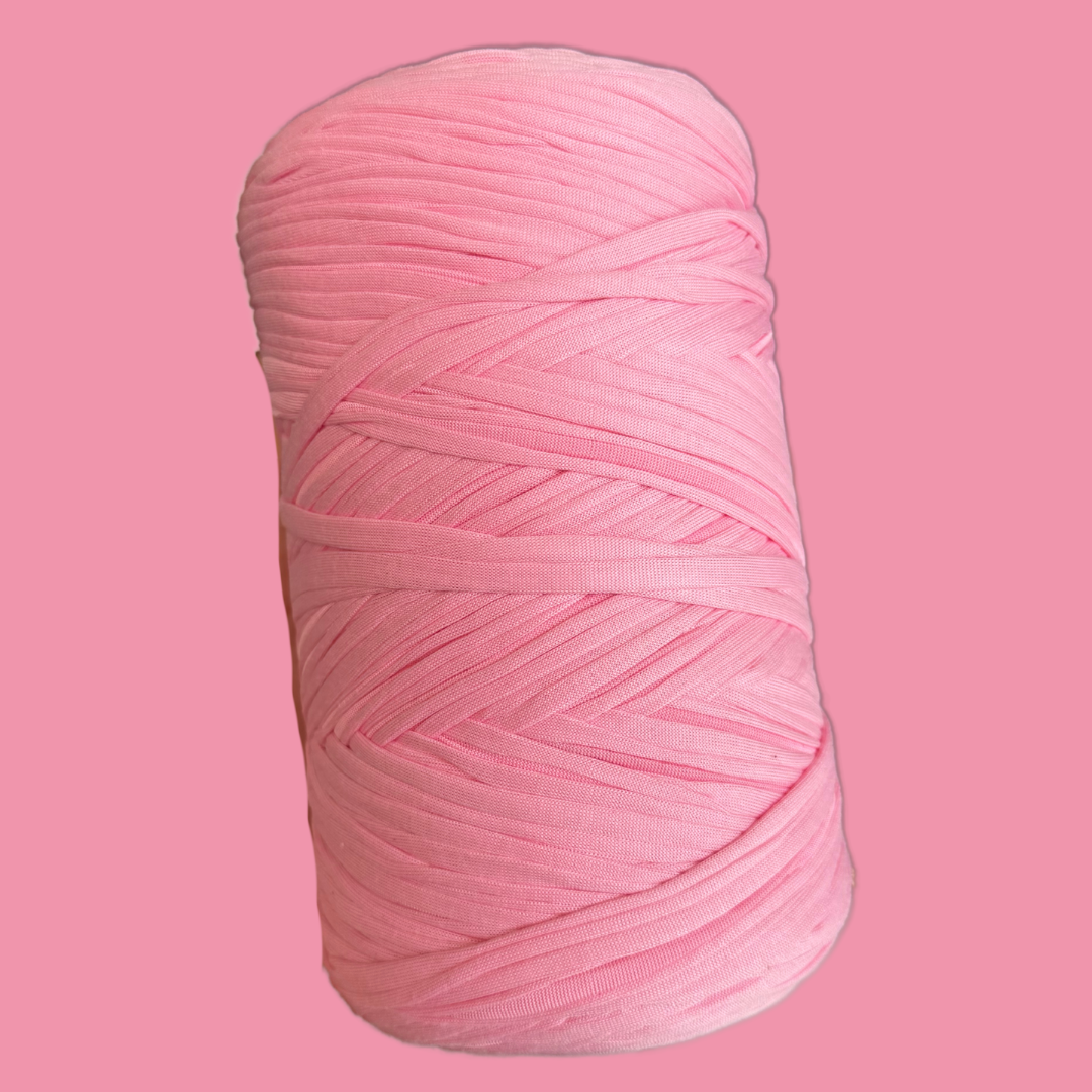 a spool of pink yarn on a pink background