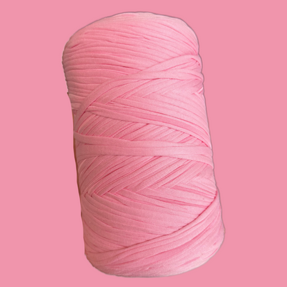 a spool of pink yarn on a pink background